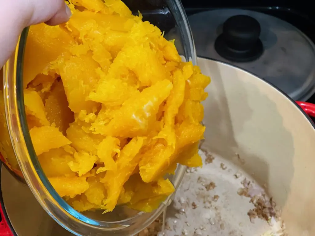 Adding a bowl full of roasted butternut squash to a Dutch oven - Domestic Gourmet