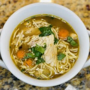 A bowl of sopa de pollo con fideos (Latin American chicken soup with noodles) made with Domestic Gourmet Organic Annatto Oil - Aceite de Achiote